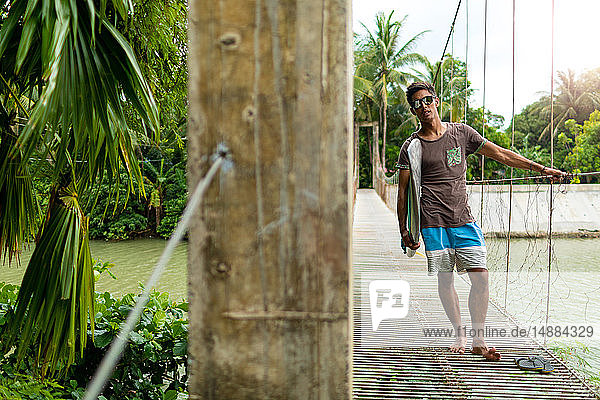 Man with surfboard on rope bridge  Pagudpud  Ilocos Norte  Philippines