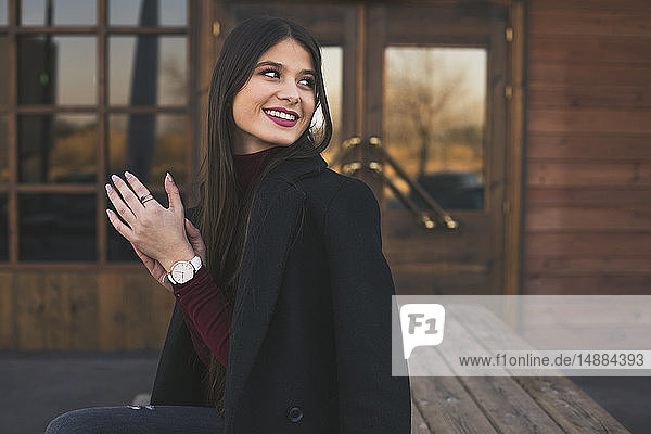 Porträt einer lächelnden Teenagerin in schwarzem Mantel
