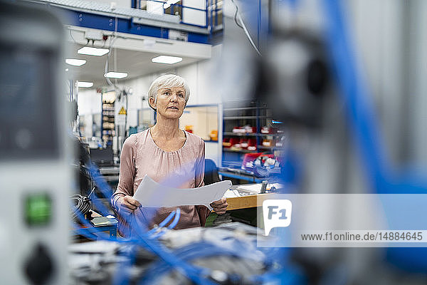 Senior woman holding plan in a factory