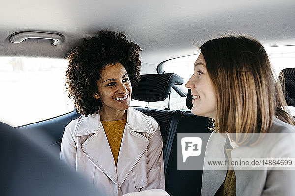 Two happy women sitting in back seat of a car