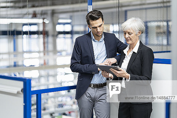 Geschäftsmann und leitende Geschäftsfrau mit Tablettengespräch in einer Fabrik