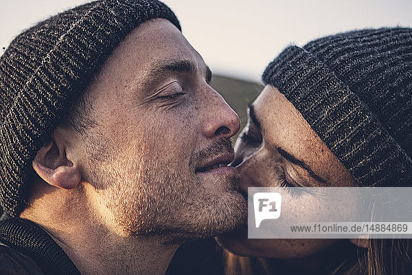 Kissing couple wearing wooly hats