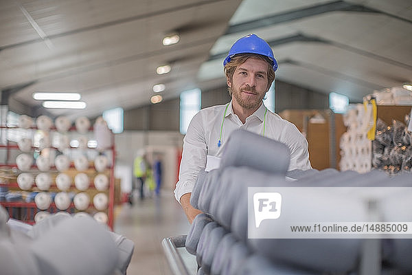 Portrait of smiling man wearing hard hat in factory