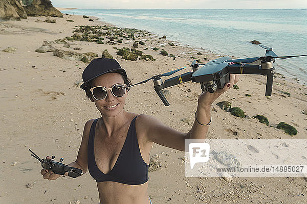 Indonesien  Bali  Nusa Dua  Frau hält Drohne am Strand