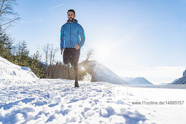 Deutschland  Bayern  sportlicher Mann rennt im Winter durch Schnee