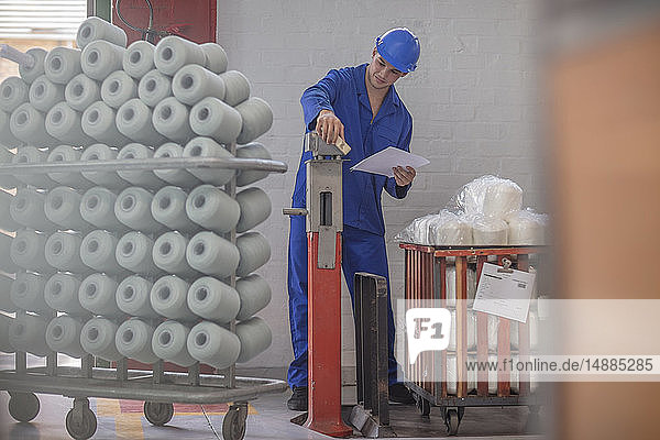Mann mit Schutzhelm kontrolliert Lieferung in der Fabrik