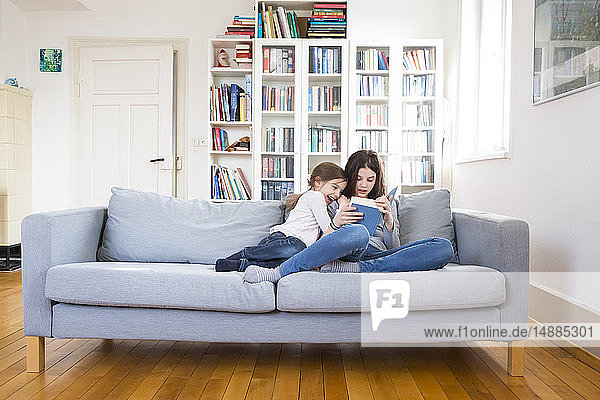 Sisters sitting on couch  reading book