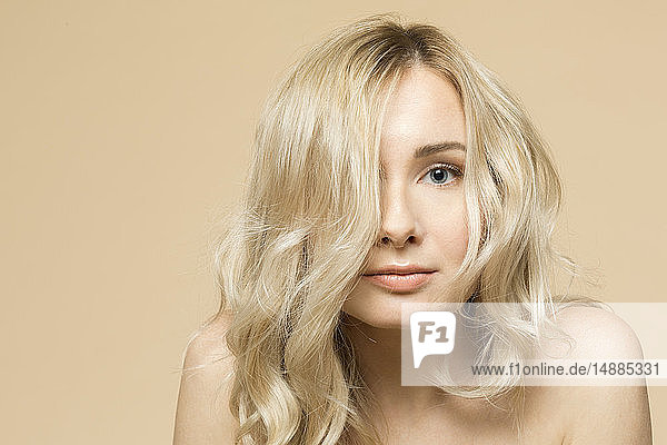 Porträt einer nackten blonden Frau vor beigem Hintergrund