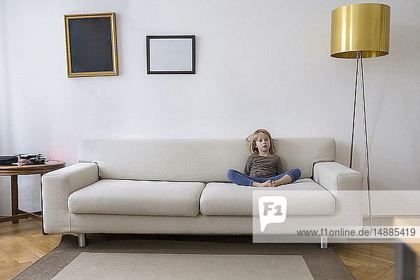 Gelangweiltes Mädchen sitzt zu Hause auf der Couch