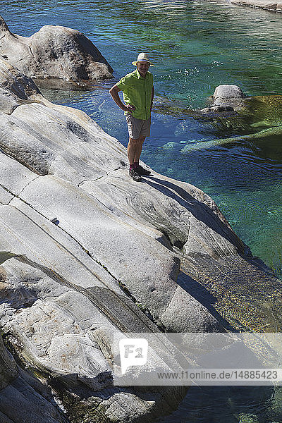 Schweiz  Tessin  Verzascatal  Mann auf Fels stehend am klaren türkisfarbenen Wasser der Verzasca