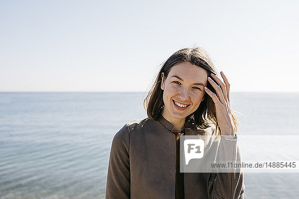 Porträt einer lächelnden Frau mit dem Meer im Hintergrund