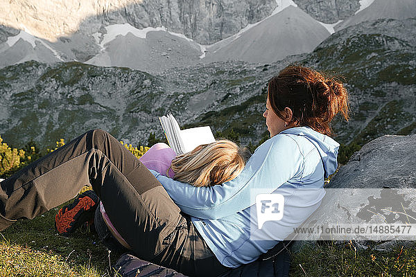 Österreich  Tirol  Mutter und Tochter lesen Buch in Berglandschaft