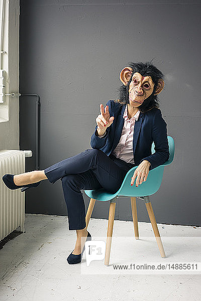 Geschäftsfrau auf Stuhl sitzend  Affenmaske tragend  gestikulierend