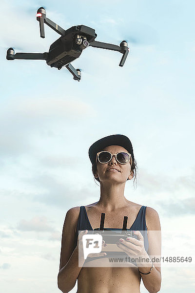 Frau fliegt Drohne unter Himmel mit Wolken