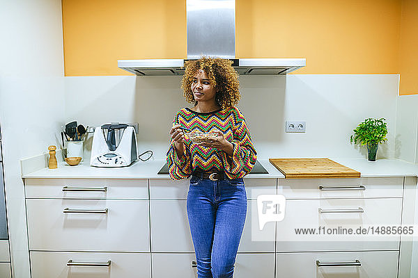Junge Frau mit lockigem Müsli in der Küche