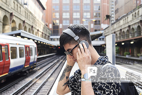 Young man listening music with headphones  standing on station