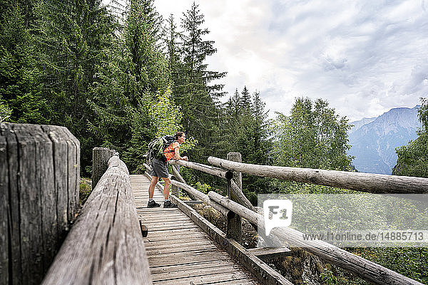 Schweiz  Wallis  Frau steht auf einer Holzbrücke während einer Wanderung auf dem Massaweg in den Bergen