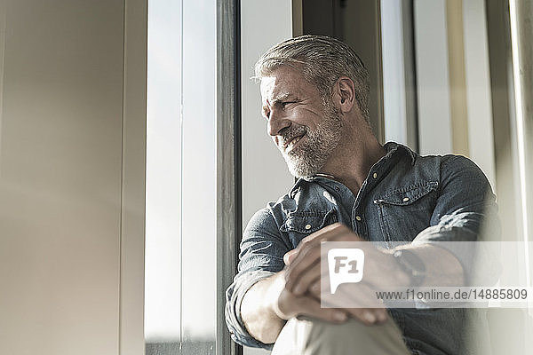 Smiling casual mature businessman looking out of window