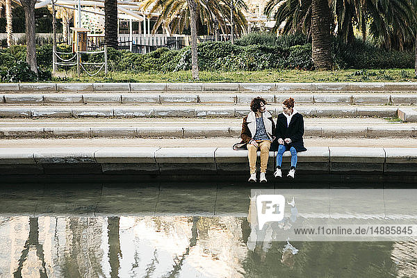 Couple sitting in a park by the water talking
