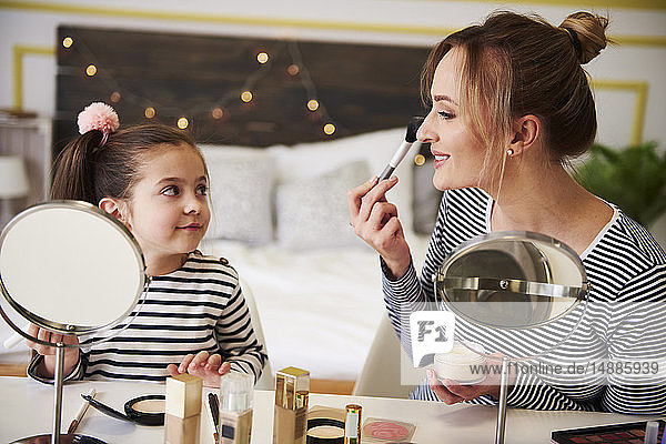 Mother and daughter applying make up together