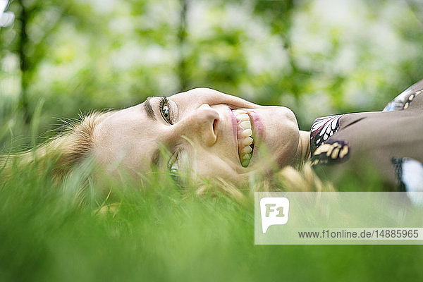 Fröhliche junge Frau liegt im Gras und entspannt sich
