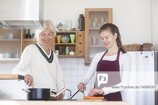Mother and adult daughter cooking together at home