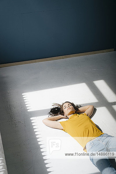 Frau liegt auf dem Boden und entspannt sich im Sonnenlicht