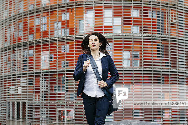 Geschäftsfrau in Bewegung vor einem Bürogebäude in der Stadt