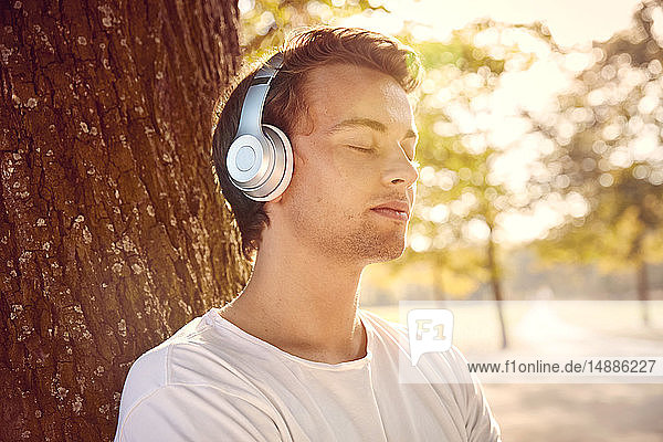 Junger Mann mit Kopfhörern  der draußen Musik hört