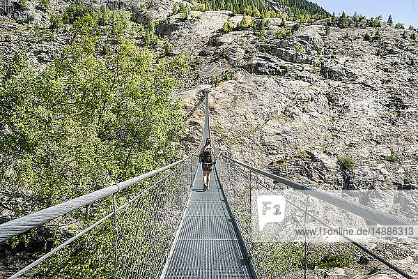 Schweiz  Wallis  Frau auf einer Wanderung in den Bergen von der Belalp zur Riederalp auf einer schwingenden Brücke