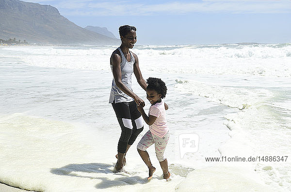 Glückliche Mutter und Tochter amüsieren sich am Strand