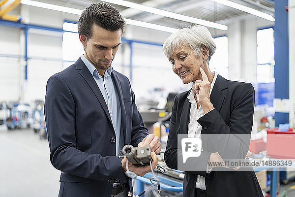 Businessman and senior businesswoman examining workpiece in a factory
