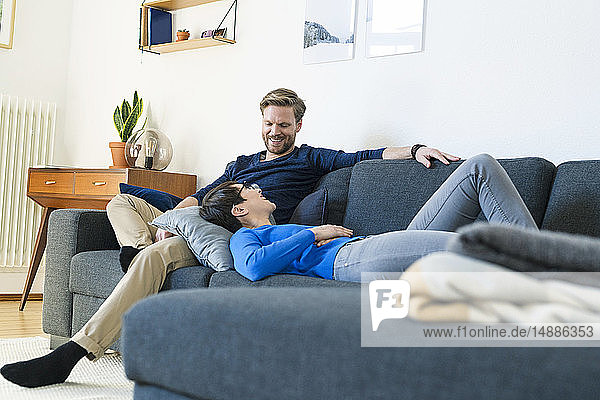 Glückliches Paar entspannt sich auf einer Couch in seinem modernen Wohnzimmer