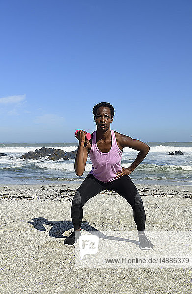 Frau beim Fitnesstraining mit Hantel am Strand