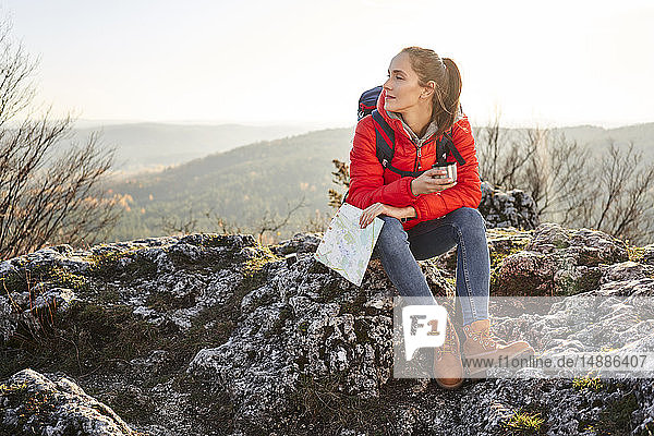 Frau auf Bergwanderung in den Bergen auf einem Felsen sitzend bei einer Pause