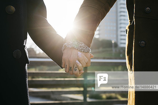 Close-up of couple holding hands in backlight