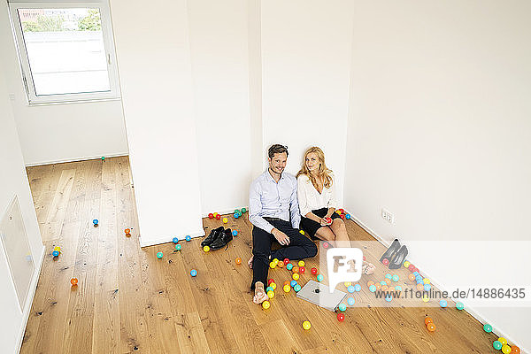 Geschäftsleute sitzen mit bunten Bällen auf dem Boden ihres neuen Hauses