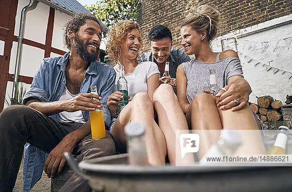 Freunde entspannen sich im Sommer in einem Hinterhof  junge Frauen kühlen ihre Füße in einer Wanne mit Getränken