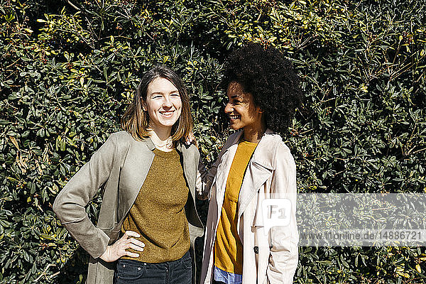 Portrait of two happy women in front of a hedge