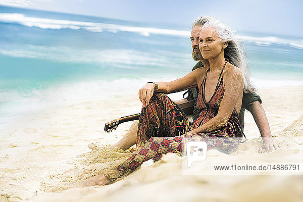 Älteres Hippie-Paar mit Gitarre entspannt am Strand