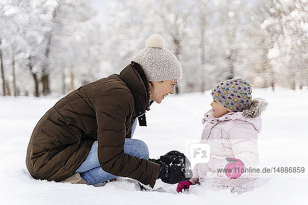 Happy mother playing with daughter in winter landscape