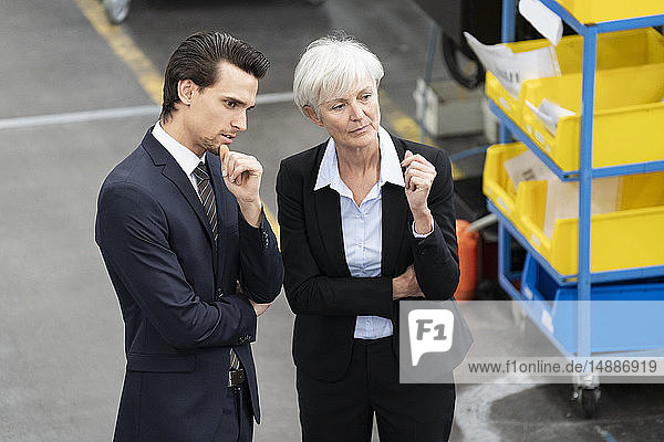 Geschäftsmann und leitende Geschäftsfrau im Gespräch in einer Fabrik