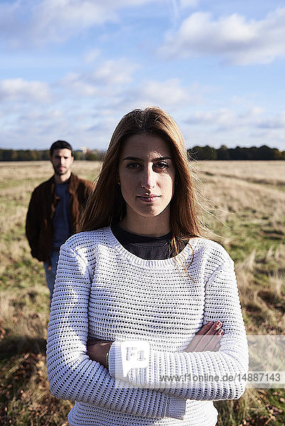 Junge Frau steht mit einem Mann hinter ihr auf einem Feld