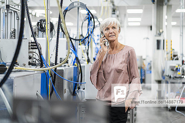 Ältere Frau am Handy in einer Fabrik