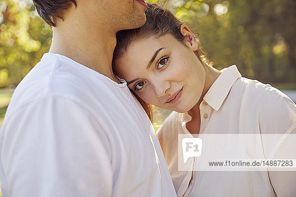 Portrait of young woman leaning against boyfriend's shoulder at a park