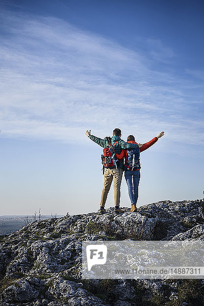 Glückliches Paar auf einer Wanderung in den Bergen auf einem Felsen stehend und die Aussicht genießend