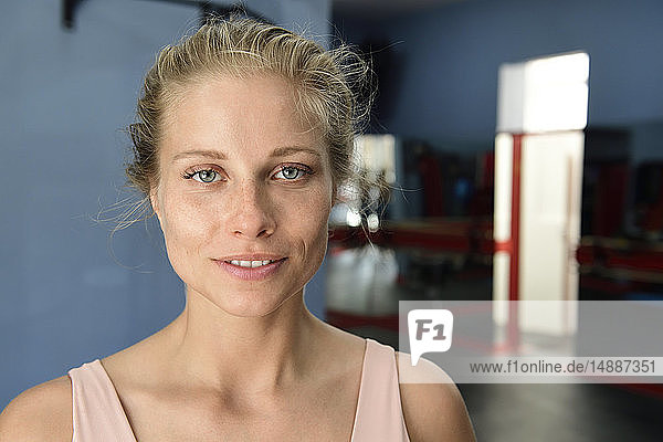 Porträt einer lächelnden jungen blonden Frau in einer Turnhalle