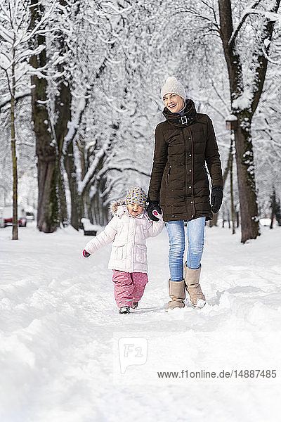 Glückliche Mutter geht mit Tochter in Winterlandschaft spazieren