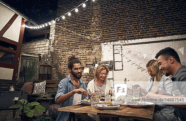 Friends having a barbecue in the backyard  eating together