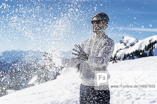 Deutschland  Bayern  Brauneck  Mann im Winter spielt mit Schnee in den Bergen